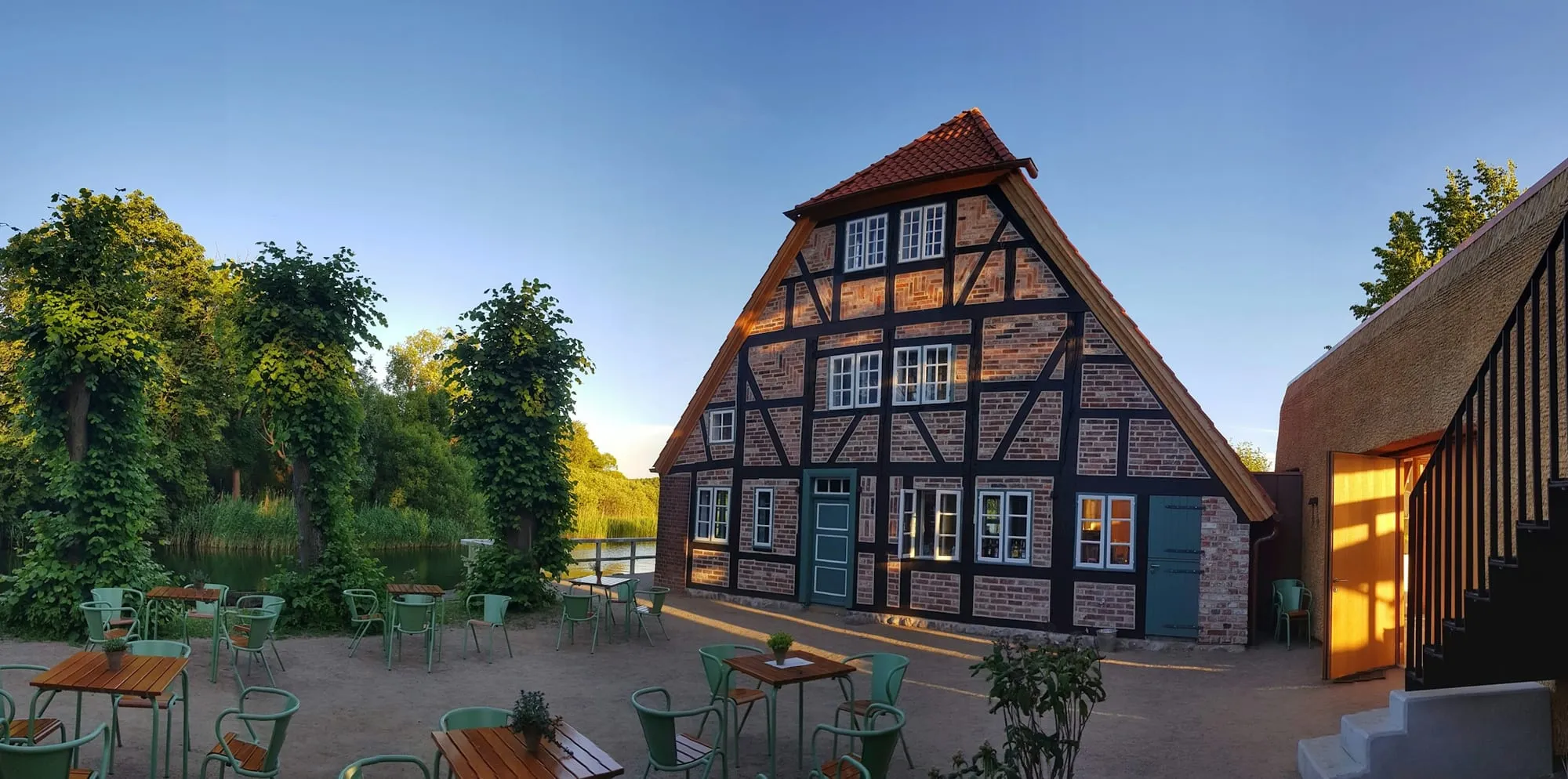 Fachwerkhaus mit Hof und Holztischen in der Abendsonne
